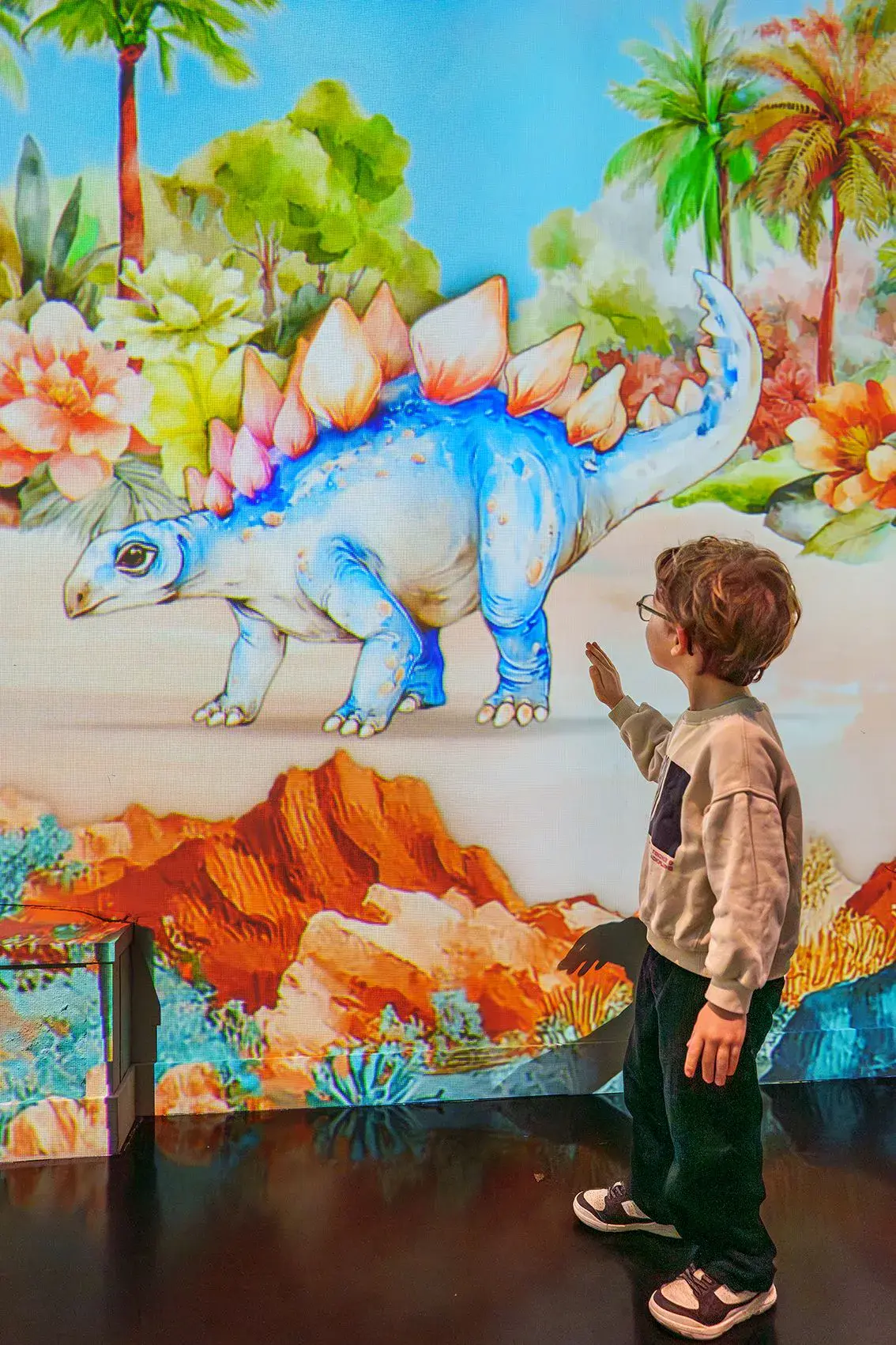 Enfant devant une projection interactive de dinosaure à l'Atelier des Lumières